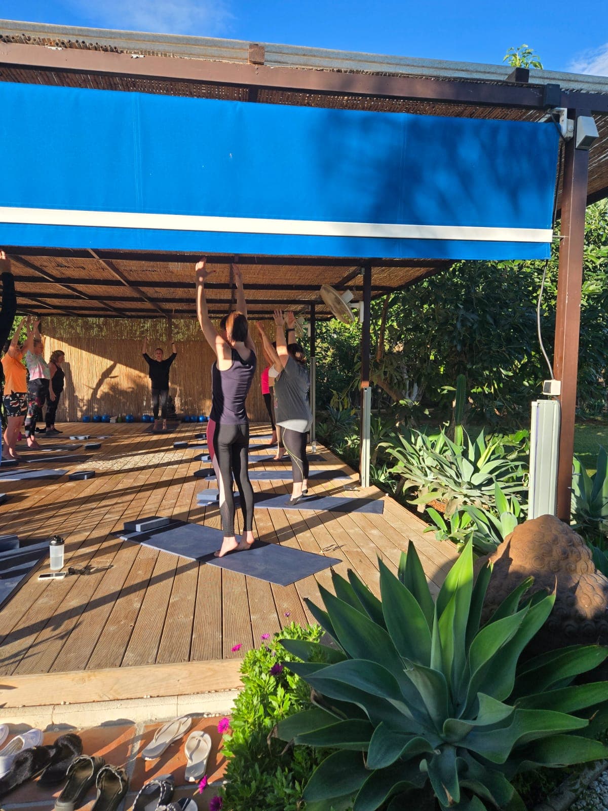 Standing Pilates exercises with arms raised in the outdoor studio
